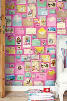 a room with pink and blue wallpaper, a white chair and some books on the floor