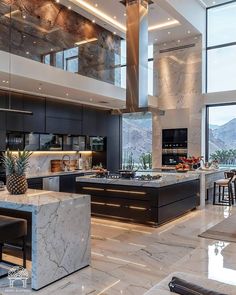 a large kitchen with marble counter tops and black cabinets, along with an island in the middle