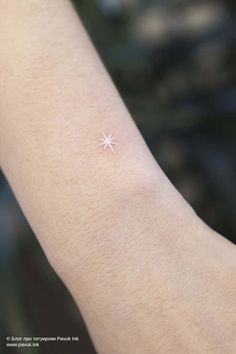 a person's arm with a small star tattoo on it