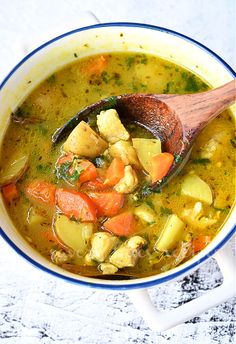 a wooden spoon in a bowl filled with chicken and vegetable soup