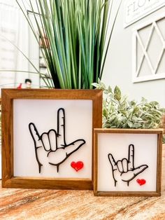 two wooden frames with hand and heart cutouts on them sitting next to each other