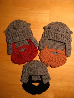 three crocheted hats with beards on top of a wooden floor next to each other