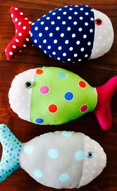 three stuffed fish sitting on top of a wooden table next to each other with polka dots