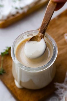 a wooden spoon in a small jar filled with white liquid on top of a cutting board