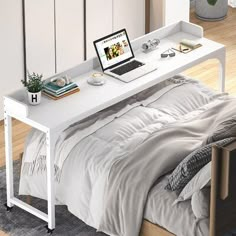 a bed with a laptop on top of it next to a white desk and chair