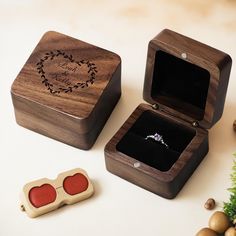 two wooden boxes with wedding rings in them on a table next to christmas decorations and ornaments