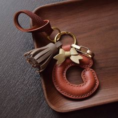 a brown leather keychain with a tassel on it sitting on top of a wooden tray