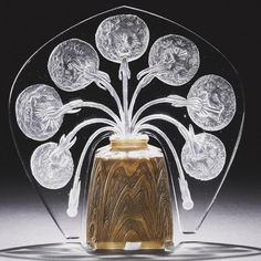 a glass vase sitting on top of a table next to a black background with white flowers