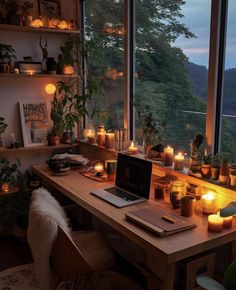 a laptop computer sitting on top of a wooden desk in front of a window filled with candles