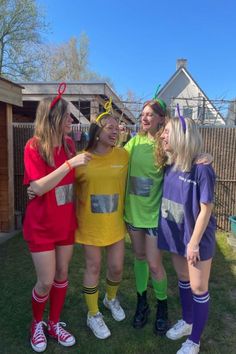 four girls in costumes standing together on the grass