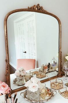 a mirror sitting on top of a dresser next to a table filled with cakes and flowers