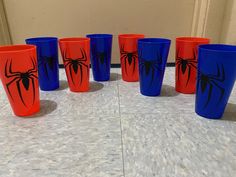 a group of blue and orange cups with spider - man designs on them sitting on a table