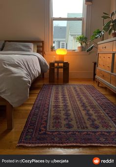 a bedroom with a bed, dresser and rug on the wooden floor next to a window