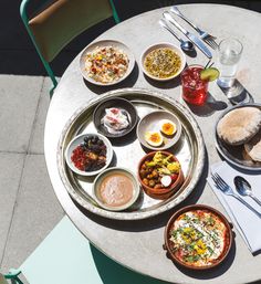 a table with plates and bowls of food on it, along with silverware and utensils