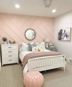 a bedroom decorated in pink and white with a chevron accent wall behind the bed