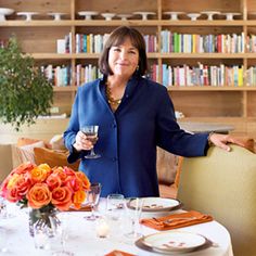 a woman holding a wine glass in front of a table with plates and glasses on it