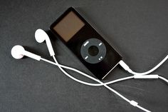 an ipod is plugged into ear buds on a black surface with white cords attached to it