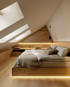 a large bed sitting in the middle of a bedroom under a slanted ceiling with lights