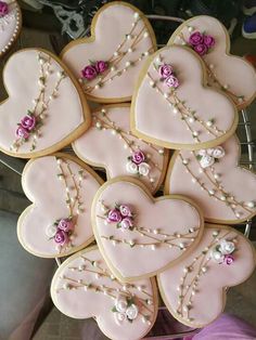 decorated cookies in the shape of hearts with pearls and pink roses on them are arranged in a basket