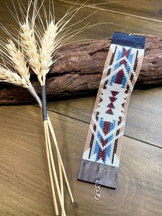 two stalks of wheat sitting next to each other on top of a wooden floor near a piece of driftwood