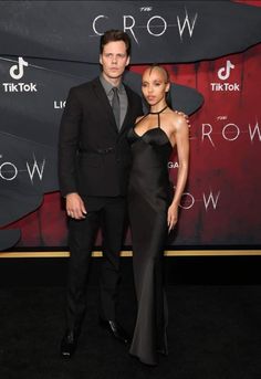 a man and woman standing next to each other on a red carpet