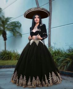 a woman in a black and gold dress with a large hat on her head