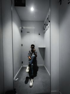 a man sitting on top of a chair next to a white wall in an elevator