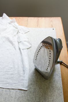 an iron sitting on top of a table next to a white shirt