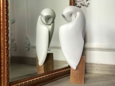 two white vases sitting on top of a wooden stand in front of a mirror