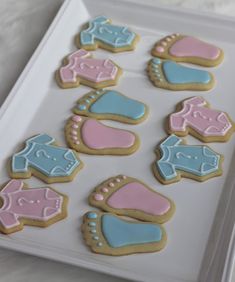 decorated cookies in the shape of baby booties and shoes on a white platter