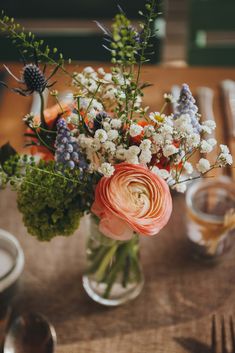 a vase filled with flowers on top of a table next to silverware and utensils