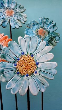 three blue and orange flowers sitting on top of each other in front of a blue wall