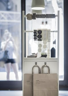 two shopping bags sitting on top of a white shelf in front of a store window