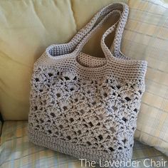 a crocheted bag sitting on top of a couch next to pillows and pillow