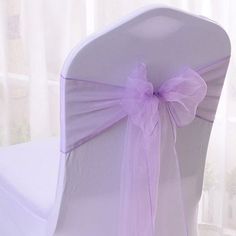 the back of a chair with purple sashes and bows on it's side