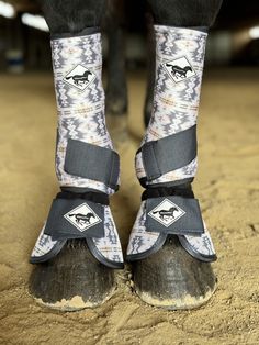 the legs and feet of a person wearing horse boots in dirt area next to building