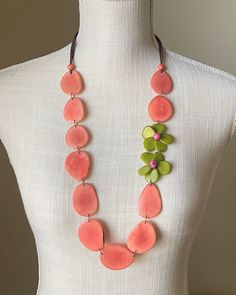 The Hibiscus necklace is our Nikki necklace with a beautiful twist. The flowers in saguaro green add a unexpected touch to the salmon tagua petals and create a vibrant color scheme.  You can pair it with even the simplest tee or dress and have a chic look in a second. Artisans in Colombia hand-carved and brightly dyed the solid petals of ivory-like tagua nut in this stunning necklace. Tagua, also called the vegetable ivory is the seed of a palm tree that grows in the tropical rainforests of seve Hibiscus Necklace, Resort Jewelry, Tagua Necklace, Tagua Jewelry, Tagua Nuts, Necklace Flower, Tropical Rainforest, Simple Tees, Necklace Long