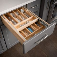 an open drawer in a kitchen with utensils and silverware on the drawers