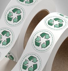 two rolls of white paper with green recycling stickers on them