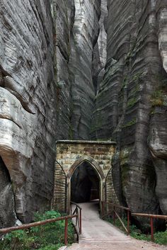 a tunnel in the side of a mountain with a stone bridge leading to it's entrance