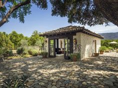 the small house is surrounded by trees and rocks, with an open patio area on one side