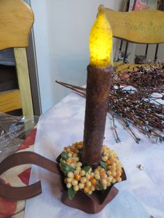 a lighted candle sitting on top of a table next to some dried flowers and branches