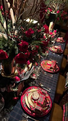 the table is set with red and black plaid place settings, silverware, and flowers