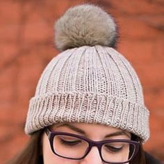 a woman wearing glasses and a knitted hat with a pom - pom