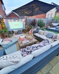 an outdoor patio with couches, pillows and a projector screen