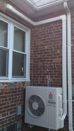 an air conditioner sitting on the side of a brick building next to a window