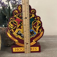 there is a ruler with the hogwarts crest on it next to a potted plant