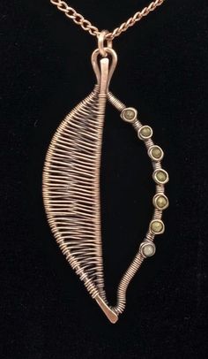 a gold necklace with green glass beads and a leaf shaped pendant on a black background