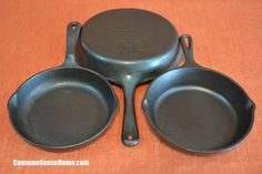 three frying pans sitting side by side on a brown tableclothed surface