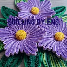 three purple flowers with green leaves on them